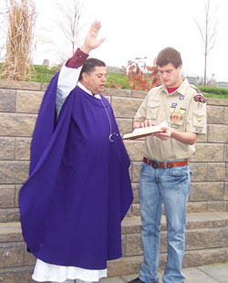 Father Juan Valdes, administrator at St. Mary Parish in Lanesville, blesses the new prayer garden on Dec. 2 on the parish&rsquo;s grounds during a dedication ceremony. He is assisted by Eagle Scout Josh Hublar, a member of the parish, who built the prayer garden for his Eagle Scout project. (Submitted photo by Leslie Lynch)