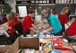 St. Matthew School students David Denise and Maddie Tarowsky, center, team up to wrap books as gifts for children in homeless shelters. The effort stemmed from the Indianapolis school&rsquo;s seventh-grade class to collect books for the school&rsquo;s library and to share them with children in need. (Photo by John Shaughnessy)