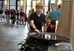 Preston Saddler, an 8th grader at St. Bartholomew School in Columbus, dips a finger into a holy water font at St. Bartholomew Church on Dec. 5, 2012, while on his way to a school Mass. In January, schools and religious education programs across the archdiocese started to use the Assessment of Catechesis and Religious Education to help learn about the knowledge and practice of students&rsquo; faith. (File photo by Sean Gallagher)