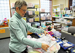 Archdiocesan Birthline coordinator Jen&aacute; Hartman examines infant clothing that is available to help new mothers and their babies who desperately need emergency assistance. (Photo by Mary Ann Garber)