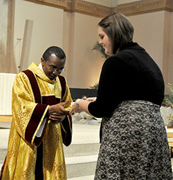 Rachel Worden, a young adult member of St. John the Evangelist Parish in Indianapolis, receives her faith community&rsquo;s holy oils from transitional Deacon John Kamwendo during the annual archdiocesan chrism Mass celebrated on March 26 at SS. Peter and Paul Cathedral in Indianapolis. (Photo by Sean Gallagher)
