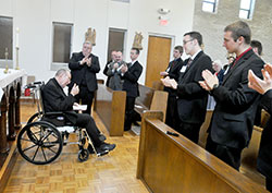 Archbishop Emeritus Daniel M. Buechlein gives a thumbs up to the seminarians and guests who applaud him after an April 21 prayer service at Bishop Simon Brut&eacute; College Seminary in Indianapolis. The retired archbishop was honored after the service for founding the seminary in 2004. (Photo by Sean Gallagher)