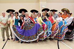 Along with native Mexican dancers, women participating in the archdiocese&rsquo;s first-ever Spanish immersion program dress in traditional folkloric dresses while the men wear sombreros with Father John McCaslin, third from left in the back row, and Franciscan Brother Moises Gutierrez, far right in the back row, during a break in the program held at Padua Academy in Indianapolis on June 7. (Submitted photo)