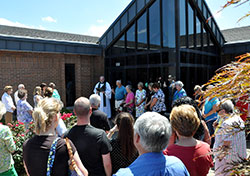 Conventual Franciscan Father Joseph West, pastor of St. Anthony of Padua Parish in Clarksville, blesses the people and the new preschool&mdash;a former credit union building located on the parish&rsquo;s property&mdash;on July 14. (Photo by Natalie Hoefer)