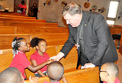 Archbishop Joseph W. Tobin greets Project SAFE students Jayonna Zinerman, left, and Mireya Benjamin on Oct. 3 at St. Andrew the Apostle Church in Indianapolis. Project SAFE (St. Andrew Faith Enrichment) is an afterschool religious education program sponsored by St. Andrew Parish for students of Andrew Academy, a public charter operated by the Archdiocese of Indianapolis on the parish&rsquo;s campus. (Photo by Sean Gallagher)