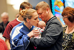 A mother kisses her child during a December 2012 Mass celebrated at Our Lady of the Greenwood Church in Greenwood. The &ldquo;10 Things&rdquo; resource says that Catholics want to work with all people of good will to build a &ldquo;civilization of love.&rdquo; (File photo by Mary Ann Garber)
