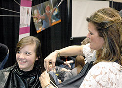 Paige Hicks, left, of the Diocese of Owensboro, Ky., is pictured with stylist Alice Hannon getting a haircut on Nov. 21. Paige was one of 40 youths at the National Catholic Youth Conference who signed up to have 10 inches of her hair cut off for &ldquo;Locks of Love,&rdquo; a program that provides wigs for financially disadvantaged children who have lost their hair because of a medical condition. (Photo by John Shaughnessy)