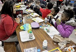 Lauren Graves, left, an eighth-grade student at St. Joan of Arc School in Indianapolis, eats lunch on Jan. 13 with Emily Wright, second from right, and Dorinda Bartone, both first-grade students at the Indianapolis North Deanery School. Graves and other older students at St. Joan of Arc help younger students during their lunch to help them develop leadership skills as a part of &ldquo;The Leader in Me&rdquo; program. (Photo by Sean Gallagher)