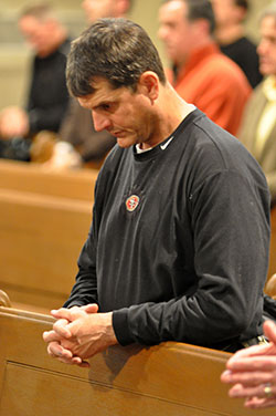 Jim Harbaugh, head coach of the National Football League&rsquo;s San Francisco 49ers, kneels in prayer during a Feb. 22 Mass at St. John the Evangelist Church in Indianapolis. NFL coaches and team officials from across the country attended the Mass and a dinner that followed. They were in Indianapolis for the annual NFL Scouting Combine, during which NFL draft-eligible college football players display their talents. (Photo by Sean Gallagher)
