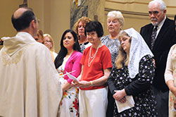 Verneta Marchant, center in the red shirt, listens as Conventual Franciscan Father Mark Weaver, pastor of St. Joseph University Parish in Terre Haute, addresses her and her fellow catechumens and candidates during the parish&rsquo;s Easter Vigil Mass on April 19. (Submitted photo)