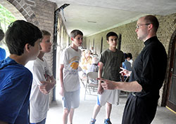 Newly ordained Father David Marcotte speaks on June 18 at Bishop Simon Brut&eacute; College Seminary in Indianapolis with Gabe Ochoa, left, Nathan Gramman, Mateo Gonzalez and Aaron Robinson, all members of SS. Francis and Clare of Assisi Parish in Greenwood. Father Marcotte, who will soon begin ministry as associate pastor of SS. Francis and Clare, spoke with the teenage boys during Bishop Brut&eacute; Days, the college seminary&rsquo;s annual camping and retreat event for young men open to the idea that God might call them to the priesthood. (Photo by Sean Gallagher)