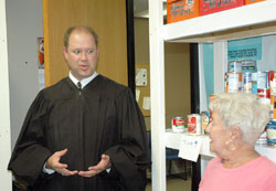 Judge David Certo of the Indianapolis Community Court visits with volunteers at the Officer David S. Moore Foundation Food Pantry, one of the court&rsquo;s many efforts to help people who have committed non-violent, non-sexual crimes turn around their lives. Marsha Fecht, a volunteer from St. Patrick Parish in Indianapolis, listens to the judge. (Photo by John Shaughnessy)