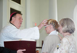 Archbishop Joseph W. Tobin anoints Kimberly Stewart as she receives the sacrament of confirmation during a Mass that the archbishop celebrated on June 29 at the Indiana Women&rsquo;s Prison in Indianapolis. Kimberly&rsquo;s mother, Theresa Stewart, rests her hand on her daughter&rsquo;s shoulder. (Photo by John Shaughnessy)
