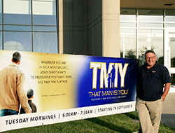 Aaron Hyre stands with a banner promoting &ldquo;That Man Is You!&rdquo; at St. Simon the Apostle Parish in Indianapolis. The new program hopes to make Catholic men grow stronger in their faith. (Submitted photo)