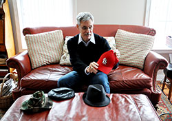 In his downtown Indianapolis home on Dec. 10, Norbert Krapf discusses the various hats he wears when giving readings from Catholic Boy Blues, a book of poems he wrote to help himself and others heal from clergy sexual abuse. The poems are written through four voices&mdash;the suffering boy, the coping adult, the wise Mr. Blues and the abusive priest. When giving readings, Krapf dons different hats to represent the various voices&mdash;the baseball cap for the boy, the fedora for the man, the flat cap for Mr. Blues and the hunting hat for the priest. (Photo by Natalie Hoefer)
