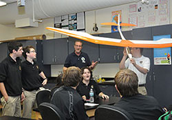 Tom Beckenbauer, middle, discusses the model plane built by Spencer Leonard, holding the model, during a Catholic Aviation Association Cupertino Club meeting at St. Theodore Gu&eacute;rin High School in Noblesville, Ind., in the Lafayette Diocese on Nov. 6, 2014. (Photo by Natalie Hoefer)