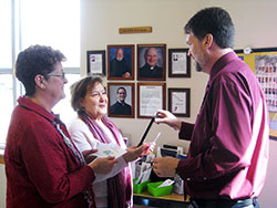 Linda Augenstein, left, and Kathy Kaler, both members of St. Jude Parish in Indianapolis, speak about vocations on Feb. 15 with Bil Danner, the parish&rsquo;s director of adult faith formation, at St. Jude&rsquo;s &ldquo;vocations station&rdquo; in the narthex of its church. Augenstein helps lead St. Jude&rsquo;s vocations committee, which maintains the vocations station. (Submitted photo)