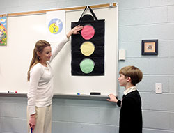 As part of the archdiocese&rsquo;s Circle of Grace program, Amy Shields uses a stoplight to explain to children how they should approach safe and unsafe touching. For example, if a parent hugs a child, that&rsquo;s a green light situation (it&rsquo;s OK for the child to hug back because the child is comfortable with the person.) If a friend at school hugs a child, it may be a yellow light situation (if the child is comfortable, then the hug is fine. If the child doesn&rsquo;t want a hug, it&rsquo;s not.) If a stranger were to hug a child, it would be a red light situation where the child would need to tell a trusted adult. A kindergarten catechism teacher at St. Paul Parish in Tell City, Shields explains the concept to her son, Griffin. (Submitted photo)