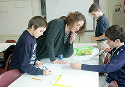 Amy Wilson&rsquo;s ability to connect with students of all academic levels is one of the reasons the fifth-grade teacher at St. Roch School in Indianapolis has been chosen as this year&rsquo;s recipient of the Saint Theodora Gu&eacute;rin Excellence in Education Award, the highest honor for a Catholic educator in the archdiocese. Here, Wilson helps Joey Luttrell, seated, with a grammar exercise while Jackson Cothron, left, works on the assignment. In the background, Anthony Stewart checks his paper. (Photo by John Shaughnessy)