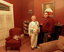 Sharon Gullett and Brent Freiberger visit the room in which Cardinal Joseph Ritter was born in the restored home at 1218 E. Elm St., New Albany. The two collaborated on a play about the cardinal&rsquo;s life. A rare portrait of Ritter hangs over the mantel behind them. (Photo by Patricia Happel Cornwell)