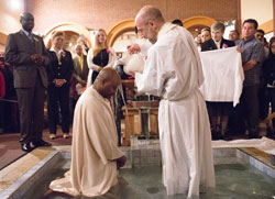 Father Todd Goodson, pastor of St. Monica Parish in Indianapolis, baptizes Gilles Noumsi during the parish&rsquo;s Easter Vigil Mass on April 4. (&copy; Denis Ryan Kelly Jr.)