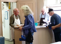 Bob Schafer, left, and Duane Miller, both members of St. Benedict Parish in Terre Haute, serve guests of the faith community&rsquo;s soup kitchen on May 22. The charitable ministry has been in operation for around 25 years in the parish that is celebrating the 150th anniversary of its founding. (Submitted photo)