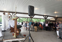 Father William Ehalt elevates the Eucharist during a May 31 Mass on the St. John the Evangelist campus of St. Catherine of Siena Parish in Decatur County. More than 300 members of the Batesville Deanery faith community took part in the Mass. Father Ehalt is St. Catherine&rsquo;s pastor. (Photo by Sean Gallagher)