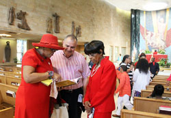 Brenda Hall, left, a member of Holy Angels Parish in Indianapolis, shares some of her poetry with fellow parishioners Jerry Monette and Anne Scott Murrell. Hall recited one of her poems during the Connected in the Spirit Pentecost Mass held on May 24 at St. Rita Church in Indianapolis. &ldquo;We must let the Holy Spirit set us free,&rdquo; one verse begins. &ldquo;Let the Holy Spirit be what it be.&rdquo; (Photo by Victoria Arthur)