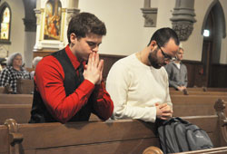 Nick Lesch, left, and Jake Firestine kneel in prayer during a Feb. 11, 2013, Mass at St. John the Evangelist Church in Indianapolis. Beginning in July, four parishes in downtown Indianapolis, as a result of the archdiocese&rsquo;s Connected in the Spirit planning process, will coordinate their daily Mass schedules and offer more opportunities for the sacrament of reconciliation. (File photo by Sean Gallagher)
