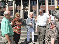 The joy of being together shows in the interaction of the organizers of the upcoming 50-year reunion involving all nine Indianapolis Catholic high schools that had graduating seniors in 1965. Steve Gutzwiller, left, Dottie Powell, Nancy Whitfield Rasmussen, Kevin Farrell and Carolyn Perrin McMahon share a laugh on the steps of the old Cathedral High School, now the Archbishop Edward T. O&rsquo;Meara Catholic Center in Indianapolis. (Photo by John Shaughnessy)