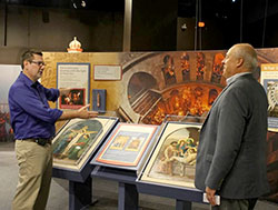 Chris Carron, left, director of collections at The Children&rsquo;s Museum of Indianapolis, guides Ken Ogorek through the museum&rsquo;s new &ldquo;National Geographic Sacred Journeys&rdquo; exhibit. Ogorek, archdiocesan director of catechesis and an exhibit advisor, helped secure two stations of the cross for a display on the Church of the Holy Sepulchre in Jerusalem. (Photo by Victoria Arthur)