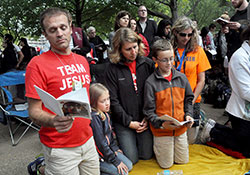 Sebastian, left, Ella, Angie and Benjamin Moster, members of St. Louis Parish in Batesville, kneel in prayer on Sept. 27 beside the Benjamin Franklin Parkway in Philadelphia during the closing Mass of the eighth World of Meeting of Families, attended by nearly 1 million worshippers. The Mosters participated in an archdiocesan pilgrimage to Philadelphia for the meeting. (Photo by Sean Gallagher)