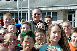 During recess at St. Vincent de Paul School in Bedford, children surround Father Rick Eldred, the pastor of that parish as well as St. Mary Parish in Mitchell, who has gained popularity with his outgoing personality and his &ldquo;Popcorn with Padre&rdquo; movie-hosting sessions at the school. (Photo by John Shaughnessy)