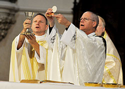 Father Rick Nagel, left, and Bishop Paul D. Etienne of Cheyenne, Wyo., elevate the Eucharist during an Oct. 31 Mass at St. John the Evangelist Church in Indianapolis. The Mass was part of the annual Indiana Catholic Men&rsquo;s Conference. Father Nagel is pastor of St. John the Evangelist Parish. Bishop Etienne, formerly pastor of St. John, was a speaker at the conference. (Photo by Sean Gallagher)