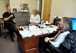 Msgr. Paul Koetter, left, pastor of Holy Spirit Parish in Indianapolis, speaks on Feb. 25 with Kathy Peacock and Suzanne McLaughlin, the parish&rsquo;s business managers, in the office of the Indianapolis East Deanery faith community. A $1 million grant recently awarded to the Archdiocese of Indianapolis by Lilly Endowment Inc. will help pastoral leaders in central and southern Indiana nurture their management skills and financial knowledge. (Photo by Sean Gallagher)