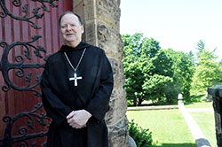 Benedictine Archabbot Kurt Stasiak stands next to the Archabbey Church of Our Lady of Einsiedeln in St. Meinrad on June 6. The monks of Saint Meinrad Archabbey elected Archabbot Kurt to be their 10th abbot and seventh archabbot in the monastery&rsquo;s 162-year history on June 2. (Photo by Sean Gallagher)