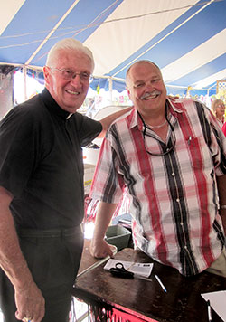 Bill Kidwell, right, is usually all smiles when it&rsquo;s time for the St. Jude Parish Festival in Indianapolis. This year&rsquo;s festival on June 23-25 will mark his 26th year of chairing the festival. Here, he poses for a photo at the 2012 festival with Father James Wilmoth, the pastor of St. Roch Parish in Indianapolis. (Submitted photo)