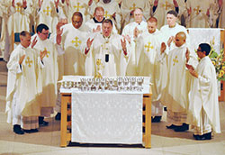 Archbishop Joseph W. Tobin prays the eucharistic prayer during a June 25 ordination Mass at SS. Peter and Paul Cathedral in Indianapolis. Joining him at the altar are, from left, Fathers Anthony Hollowell, James Brockmeier, Douglas Hunter, Kyle Rodden, Matthew Tucci and Nicol&aacute;s Ajpacaj&aacute; Tzoc, who were all ordained to the priesthood during the liturgy. Standing behind them are, from left, Deacon Stephen Hodges, Father Patrick Beidelman, Deacon Scott Bowman of the Colorado Springs, Colo., Diocese and Bishop James F. Checchio of the Metuchen, N.J., Diocese. (Photo by Sean Gallagher)