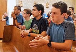 Kneeling in prayer during the June 16 Mass are John Paul Malinoski, left, Patrick Barron, Leo Ocampo&mdash;all members of Our Lady of the Most Holy Rosary Parish in Indianapolis&mdash;and Isaac Williams, a member of St. John the Apostle Parish in Bloomington. 