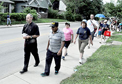 Father Christopher Wadelton, pastor of St. Philip Neri Parish in Indianapolis, leads a group in praying the rosary on July 10 while walking through the neighborhood surrounding the faith community on the city&rsquo;s near east side. The parish is sponsoring a series of nine consecutive prayer walks in response to increased drug problems and violent crimes in its neighborhood. (Photo by Sean Gallagher)