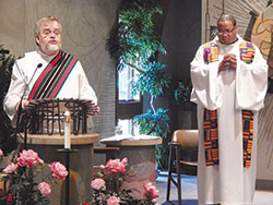 Deacon Kerry Blandford, parish life coordinator of St. Andrew the Apostle Parish in Indianapolis, left, proclaims the Gospel during a Sept. 9 prayer service in the parish&rsquo;s church. Also pictured is Father Douglas Hunter, associate pastor of St. Pius X Parish and chaplain coordinator at Bishop Chatard High School, both in Indianapolis. (Photo by Mike Krokos)