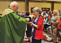 Sharon O&rsquo;Brien, director of the Catholics for Family Peace Education and Research Initiative at the Catholic University of America in Washington, receives Communion from Archbishop Joseph E. Kurtz during the Sept. 10 closing Mass of the National Council of Catholic Women convention held at the Downtown Marriott in Indianapolis. (Photo by Sean Gallagher) 