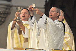 Father Rick Nagel, left, and Bishop Paul D. Etienne of Cheyenne, Wyo., elevate the Eucharist during an Oct. 31, 2015, Mass at St. John the Evangelist Church in Indianapolis during the Indiana Catholic Men&rsquo;s Conference. On Oct. 4, it was announced that Pope Francis has named Bishop Etienne as the fourth archbishop of Anchorage, Alaska. (Criterion file photo by Sean Gallagher)