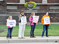 Heidi Hughey of St.&nbsp;Therese of the Infant Jesus (Little Flower Parish) in Indianapolis, left, Andrea Fleck of St. Roch Parish in Indianapolis, and Alice and Jackie Hughey, also of Little Flower Parish, hold signs in front of the Archbishop Edward T. O&rsquo;Meara Catholic Center during the Life Chain event in Indianapolis on Oct. 2. (Photo by Natalie Hoefer)