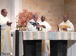 Father Michael Hoyt, second from left, pastor of St. Michael the Archangel Parish in Indianapolis, prays the eucharistic prayer during the archdiocesan St. Martin de Porres Mass celebrated on Nov. 3 at his parish&rsquo;s church. Also pictured are Father Douglas Hunter, left, Father Kenneth Taylor and Society of the Divine Word Father Charles Smith. (Photo by Mike Krokos) 
