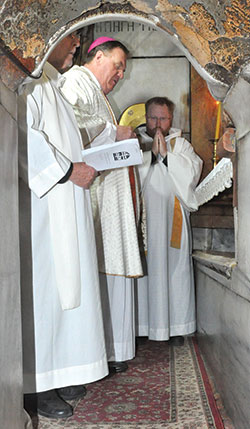 Archbishop Joseph W. Tobin, center, celebrates Mass at the site venerated as Christ&rsquo;s tomb in the Church of the Holy Sepulcher in Old City Jerusalem on Feb. 13, 2015. He is assisted by Father Robert Mazzola, left, and Father Joseph Newton, right. (File photo by Natalie Hoefer)