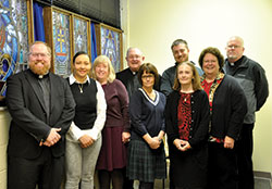 Father Joseph Newton, left, archdiocesan vicar judicial, poses on Nov. 29, 2016, with fellow staff members in the archdiocesan metropolitan tribunal. They are, from left, Swiden Torres-Torrijos, Ann Tully, Msgr. Frederick Easton (retired vicar judicial and now adjunct vicar judicial), Nancy Thompson, Joseph Gehret, Kay Summers, Peggy Crawford and Benedictine Father Patrick Cooney. The staff posed in the St. Alphonsus Liguori Chapel in the Archbishop Edward T. O&rsquo;Meara Catholic Center in Indianapolis. Not pictured is Daniel Ross, a recent addition to the tribunal staff. (Photo by Natalie Hoefer)