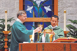 Father David Bu Nyar, right, celebrates Mass with the assistance of Deacon Thomas Horn, St. Mark the Evangelist Parish&rsquo;s pastoral associate, at St.&nbsp;Mark the Evangelist Church on Feb. 11. Father Bu Nyar was invited by then-Archbishop Joseph W. Tobin to come from Myanmar to serve the refugees of that country now worshipping at St. Mark and St. Pius X parishes in Indianapolis. (Photo by Natalie Hoefer)	