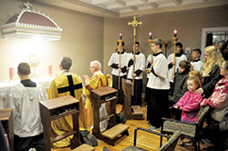 Father Jonathan Meyer, pastor of All Saints Parish in Dearborn County, second from left, and Deacon Robert Decker, joins several altar servers and other parishioners in praying before the Blessed Sacrament on March 1 in the Batesville Deanery faith community&rsquo;s new perpetual adoration chapel on its St. John the Baptist campus in Dover. (Photo by Sean Gallagher)