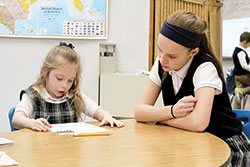 Sixth-grader Chloe Griffin, right, works with first-grader Avery Pierce at St. Gabriel School in Connersville. The school&rsquo;s sixth-grade students are giving up their recess during Lent to help other students. (Submitted photo)